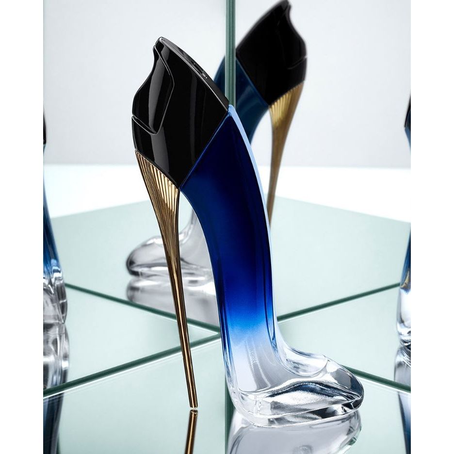 Blue stiletto-shaped perfume bottle with gold heel, reflected on mirrored surface