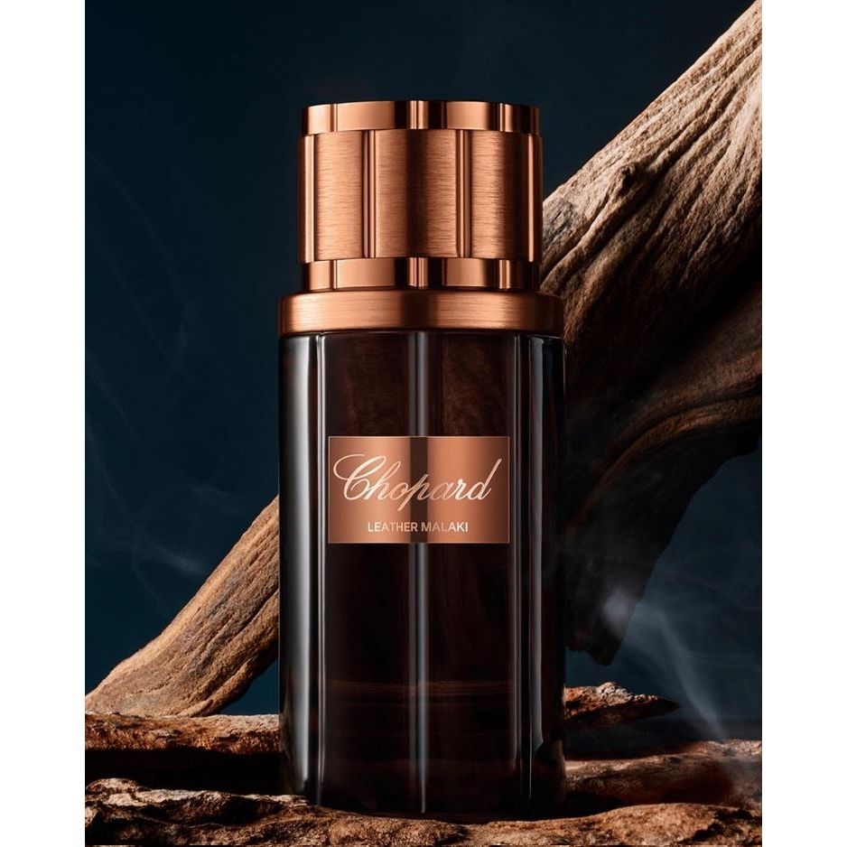 Chopard Leather Malaki perfume bottle with metallic bronze cap on wood background