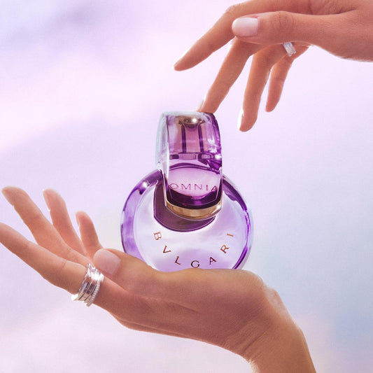 Bvlgari Omnia perfume bottle held gently in hands, purple glass design, luxury fragrance