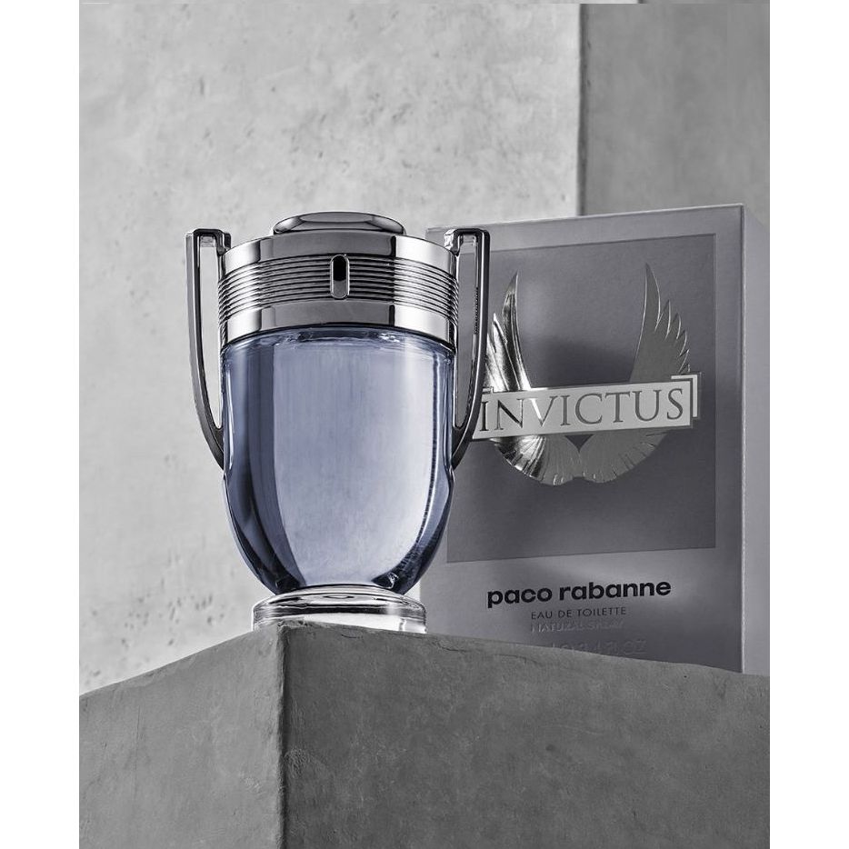 Invictus men’s eau de toilette 100ml grey trophy-shaped perfume bottle with box on concrete.