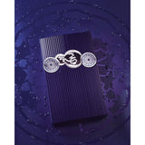 Luxury purple perfume box with ornate silver emblem, featuring Arabic script and intricate designs on a geometric background.