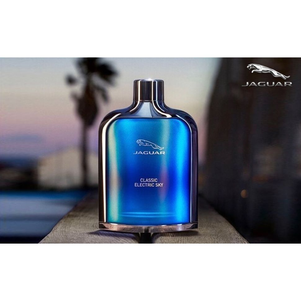 Jaguar Classic Electric Sky blue perfume bottle on outdoor table at sunset with palm tree background