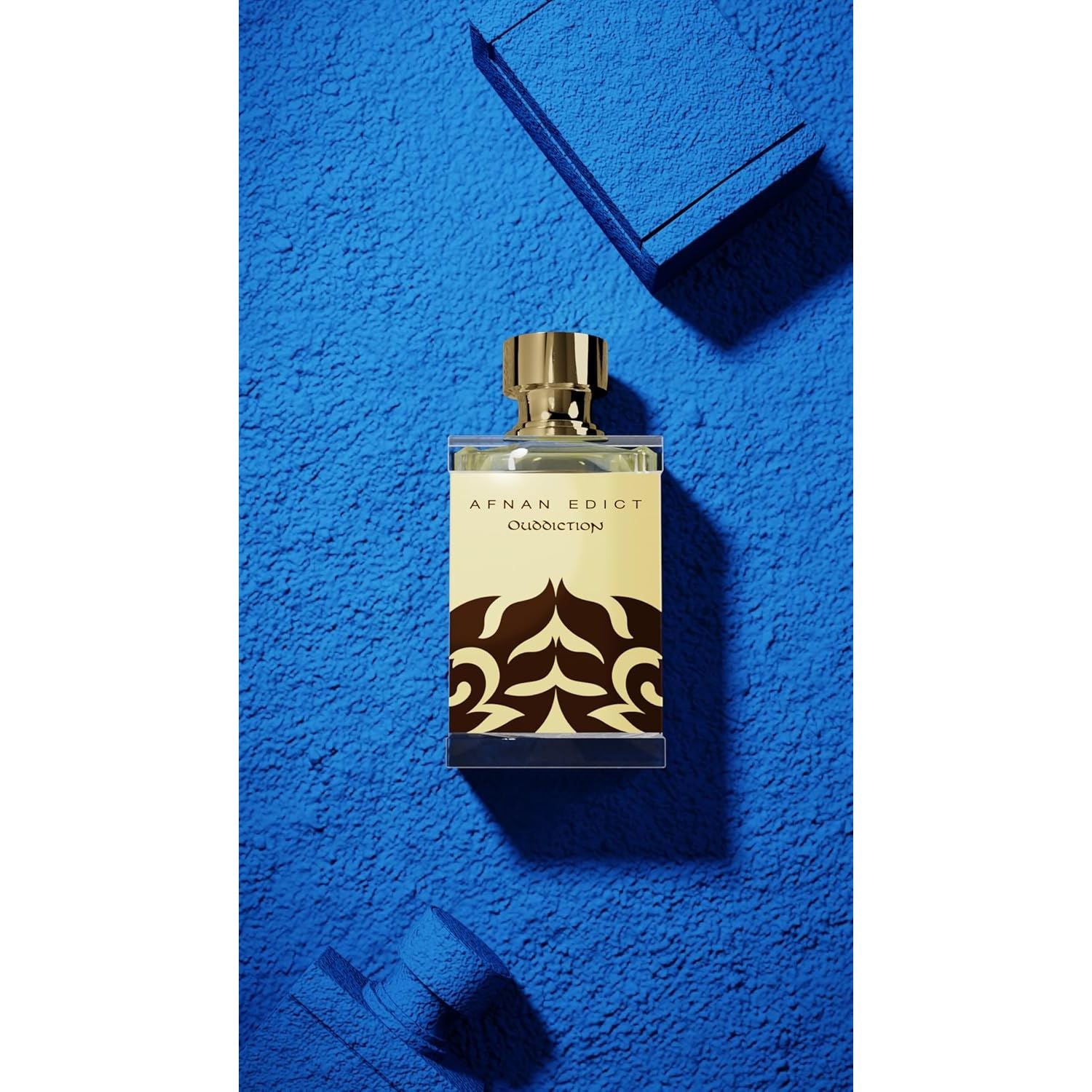Afnan Edict Oudiction perfume bottle with gold cap on textured blue background