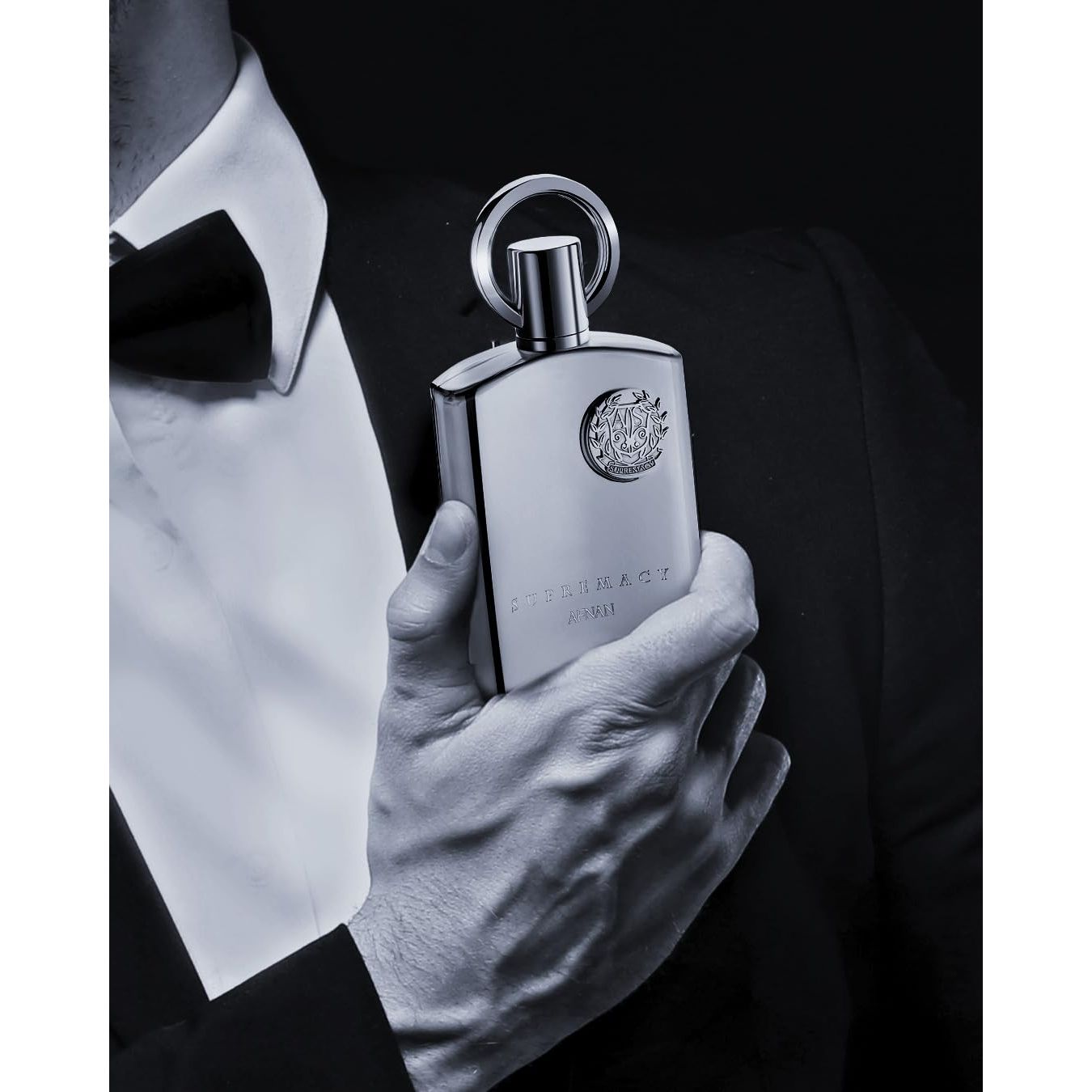 Man in tuxedo holding Supremacy Afnan luxury perfume bottle, elegant Arabic fragrance for formal occasions