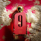 Afnan 9am pour femme perfume bottle with gold cap on red and gold textured background