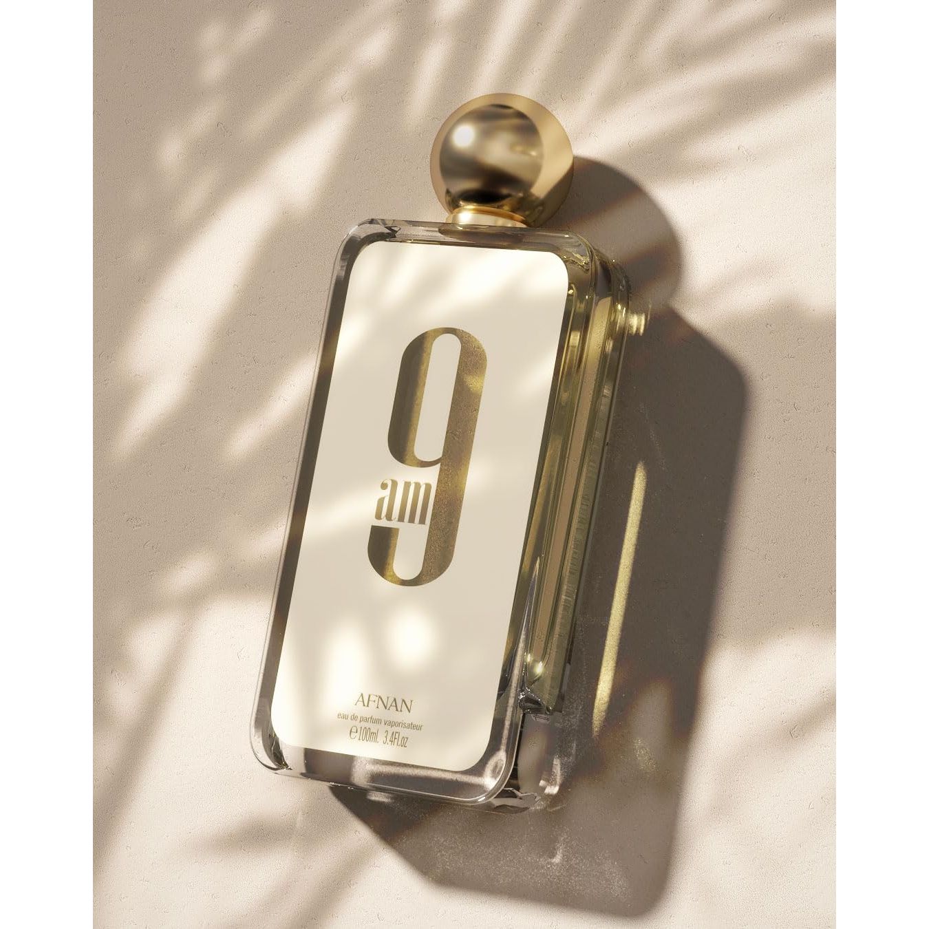 Afnan 9am perfume bottle with gold cap on sunlit textured surface, luxury fragrance