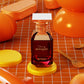 Afnan Cherry Bouquet perfume bottle with gold accents on orange background, surrounded by beauty accessories.