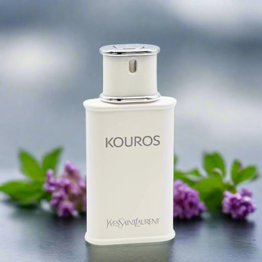 KOUROS white perfume bottle with silver accents beside purple flowers and green leaves