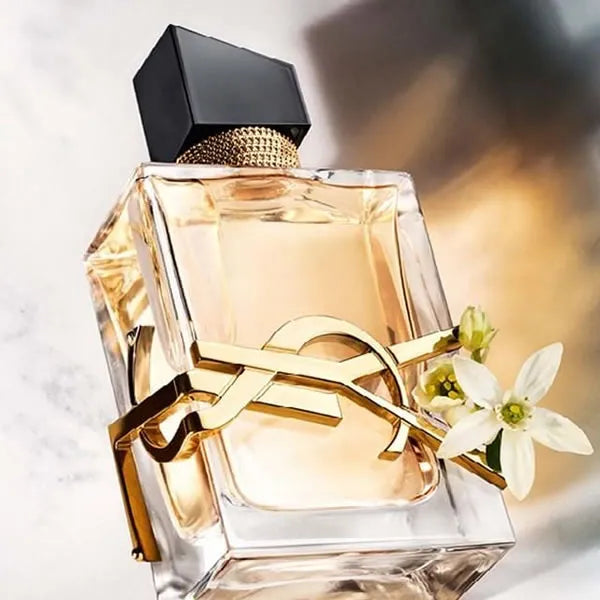 Elegant perfume bottle with gold accents and white flowers on a marble surface