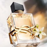 Elegant perfume bottle with gold accents and white flowers on a marble surface
